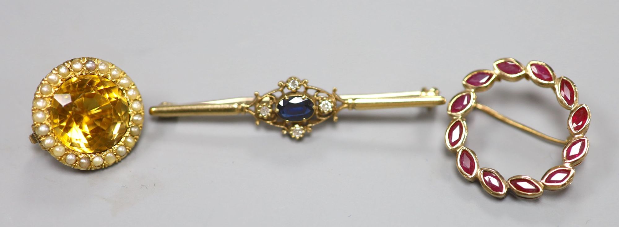 A 9ct gold sapphire and diamond bar brooch, a 14ct and ruby wreath brooch and a yellow tourmaline and seed pearl cluster brooch (3)